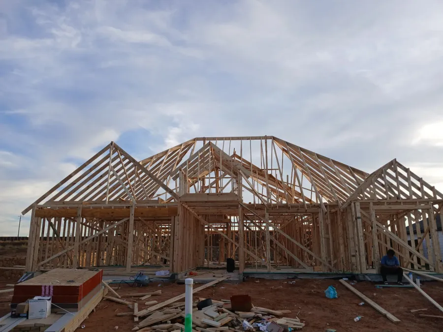 Front elevation of a framed house at dusk with lumber stacked on site