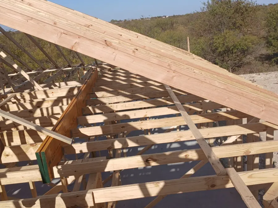 Overhead view of ceiling joists and rafters laid out across a house frame