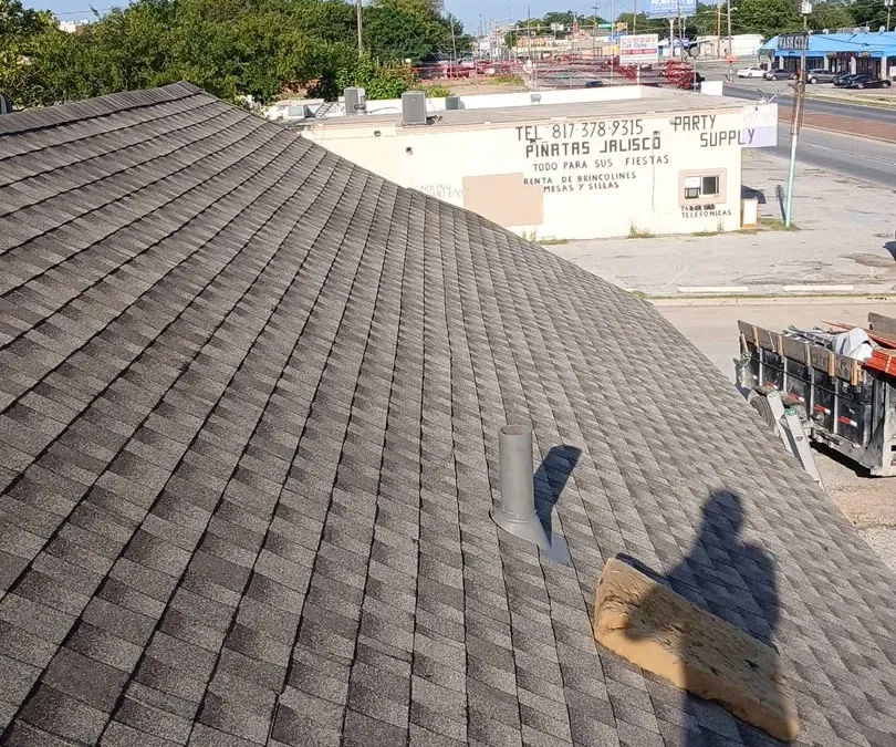 Long low-slope shingle roof over a commercial building on a main road