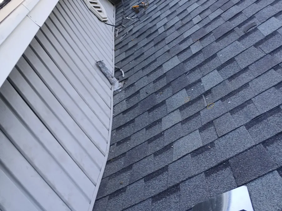Roof valley meeting a sided dormer wall with a gable vent above
