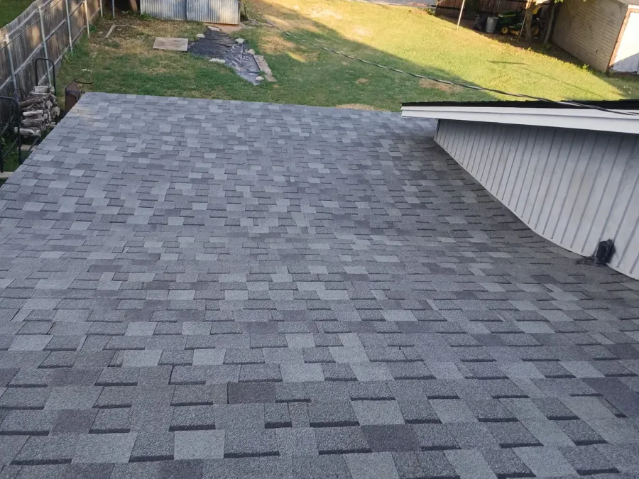 Wide roof slope of fresh shingles above a fenced backyard