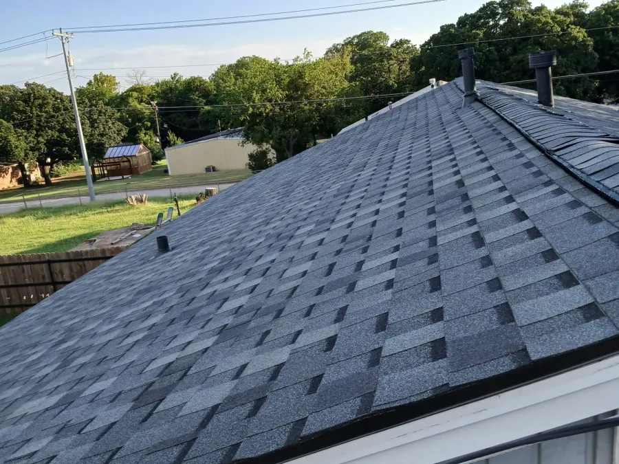 Completed hip roof in grey architectural shingles at golden hour