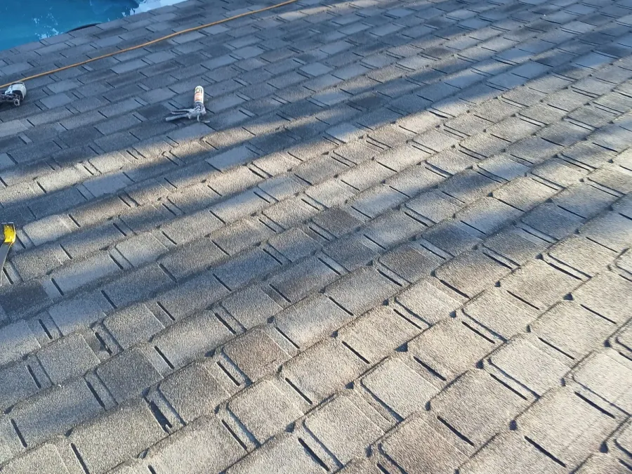 Shingle roof replacement on a stone home overlooking a backyard pool